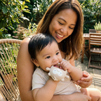 Baby wearing the Bubzies teething mitten on a sunlit garden patio