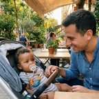 Baby in a stroller with the Bubzies pacifier clip keeping the soother off the ground at an outdoor cafe