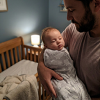 Newborn swaddled in the Bubzies sleep sack in a blue-grey nursery