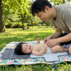 Father changing baby on the Bubzies portable pad at the park